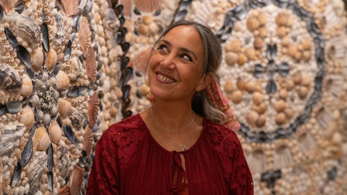 Monica-Shanta, artist of the Room of Discovery, in front of the shell panels, A la Ronde, Devon.